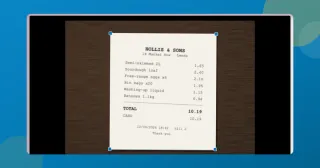 ToolsTray's document scanner in Crop mode: a till receipt photographed on a wooden desk, with the four corner handles sitting on the paper's edges.